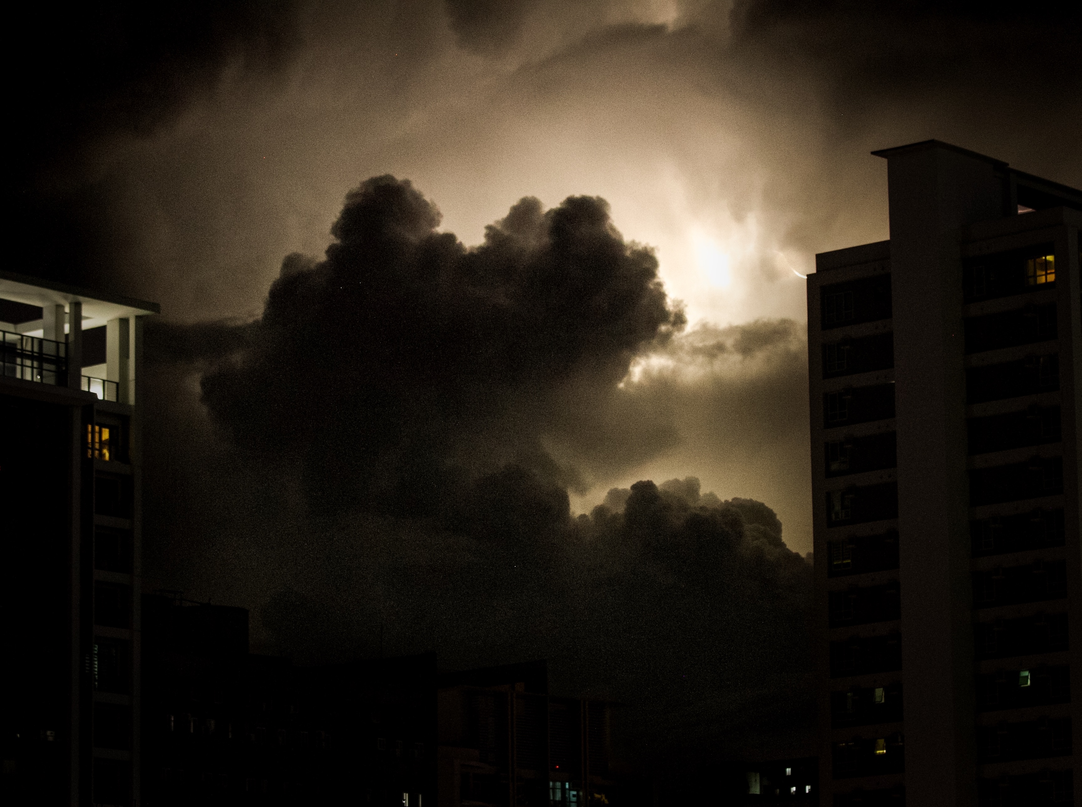 Storm clouds lit from behind, between two Makati towers at night